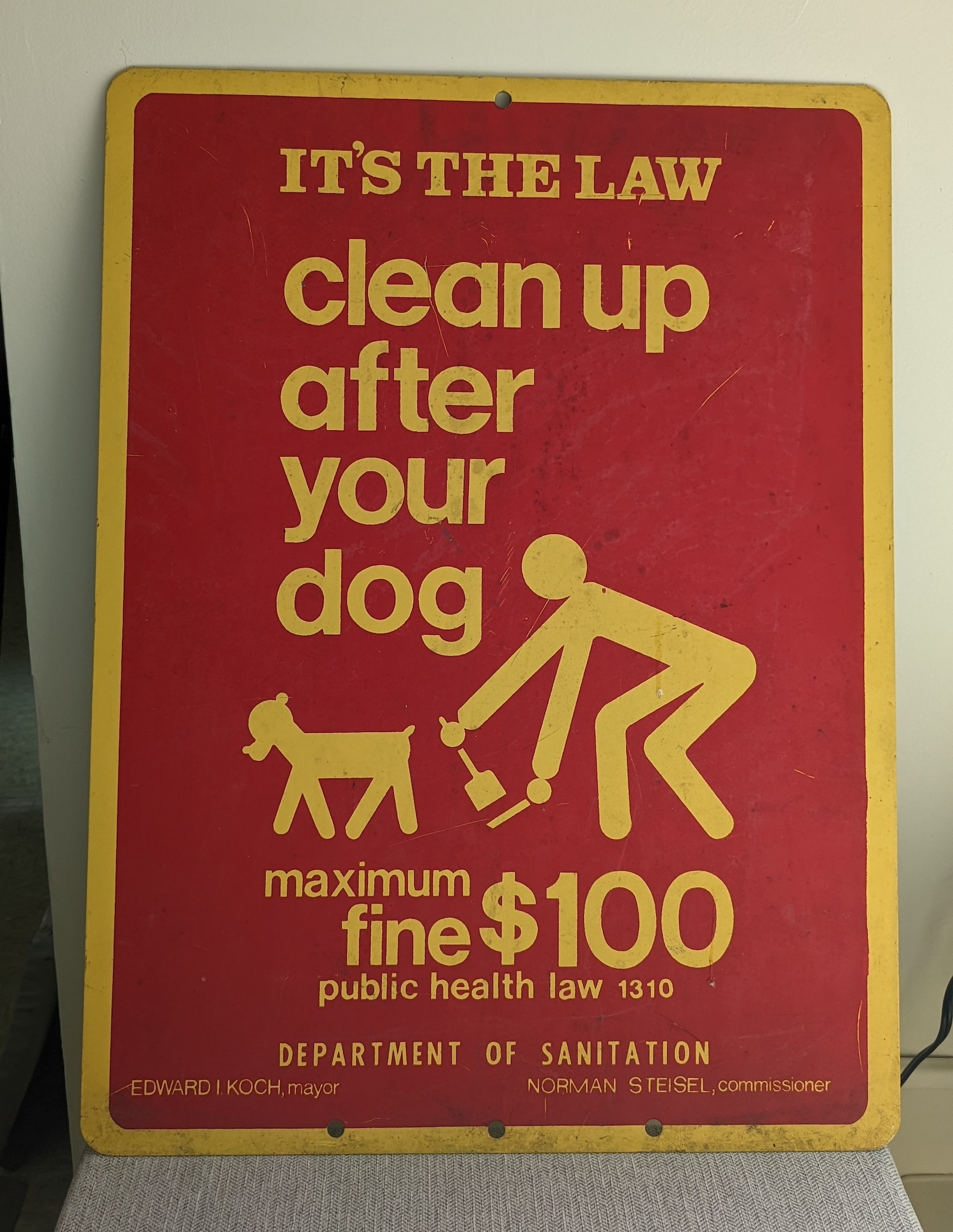 A street sign reading: "IT’S THE LAW. Clean up after your dog."